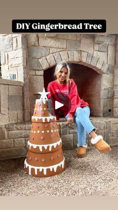 a woman sitting on top of a fake gingerbread tree next to a fire place