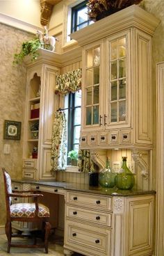 an old fashioned kitchen with white cabinets and green vases on the counter top in front of it