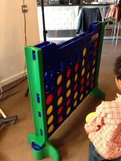 a little boy playing with a giant connect game