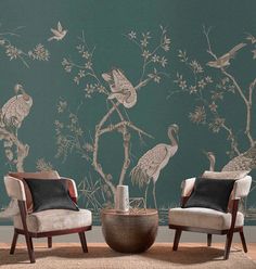 two chairs and a table in front of a wall with birds on it