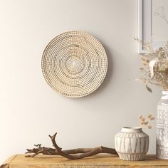 two vases are sitting on a table next to a wall with a wicker basket