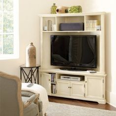 a living room with a large tv on top of a white entertainment center next to a window