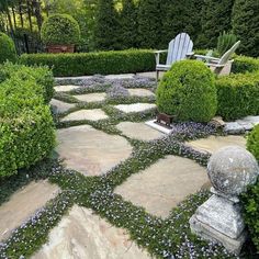 a stone walkway surrounded by bushes and chairs