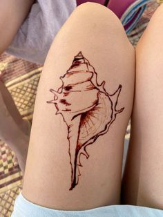 a close up of a person's legs with a tattoo on their leg and a sea shell