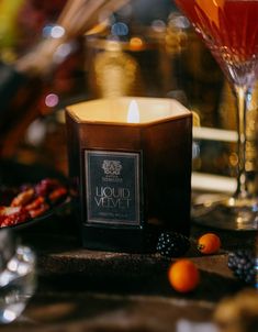 a candle sitting on top of a table next to some fruit and wineglasses