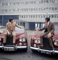 two men in suits sitting on top of cars