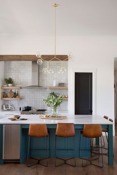 a kitchen with blue cabinets and white counter tops, wooden flooring and hanging lights