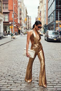 Feel a million dollars when dressed in the TIANNA Gold Jumpsuit, a luxurious high-shine design. This halter neck jumpsuit is adorned with exclusively designed gold sequins and features fixed knot twist detailing to the front, forming elegant pleats to create a sculpting finish. This figure-hugging jumpsuit is finished with flared trousers, a concealed zip to the back, and is fully lined for a smooth and comfortable fit.

#gold #occasionwear #jumpsuit Gold Jumpsuit, Halter Neck Jumpsuit, Sequin Halter