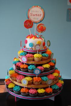 a multi - tiered cake decorated with cupcakes and lollipops