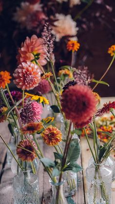 several vases filled with flowers sitting on top of a wooden table next to each other