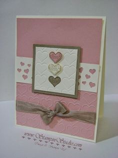 a pink and white card with two hearts on the front, one has a bow