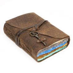 a brown leather journal with a key on the front and two different colored pages inside