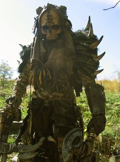 a man made out of metal and wood in the grass with horns on his head