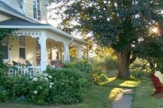 the sun shines brightly in front of a house with flowers and bushes around it