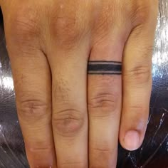 a person's hand with a ring on it and a black band around the middle finger