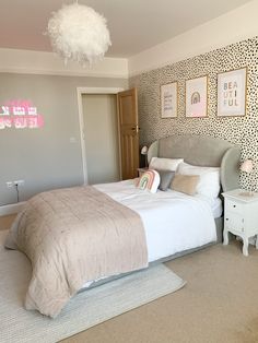 a bed room with a neatly made bed and pictures on the wall above it's headboard