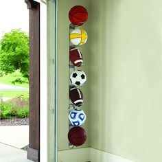 a basketball and soccer balls hanging on the wall next to an open door with grass in the background