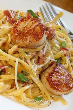 some scallops are on top of pasta and garnished with parmesan cheese