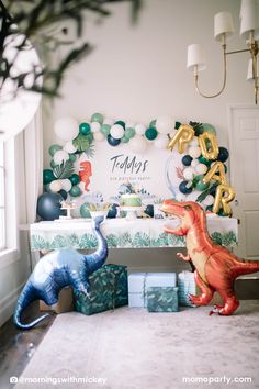 two dinosaur figurines sitting on top of a table next to boxes and balloons