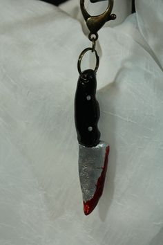 a black and red object hanging from a metal hook on a white cloth covered surface