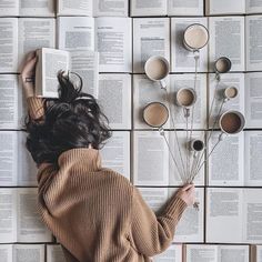 a woman laying on top of an open book covered in pages and holding some flowers