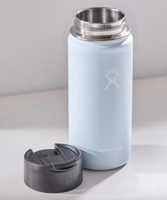 a blue water bottle next to a cup on a white counter top with a lid