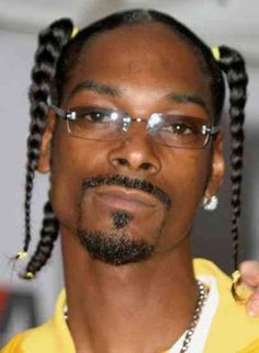 a man with glasses and braids on his head is posing for the camera while wearing a yellow shirt