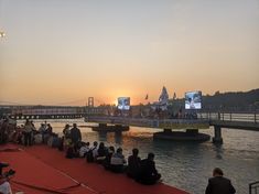 people are sitting on the edge of a bridge watching tvs in the evening sun