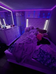 a bed room with a neatly made bed and purple lights