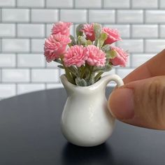 a small white vase with pink flowers in it