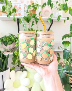 two mason jars with straws painted on them in front of some potted plants