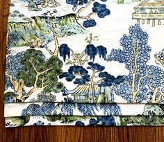 two placemats with blue and white designs on them sitting on a wooden table