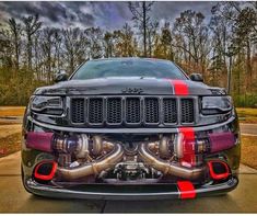 the front end of a black jeep with red stripes on it's hood and exhaust pipes