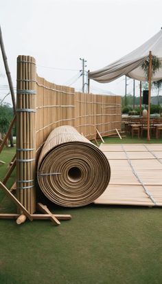 a large roll of wood sitting on top of a grass covered field next to a fence