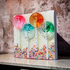 three lollipops sitting on top of a table with sprinkles