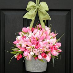 a bucket filled with pink tulips sitting on top of a door