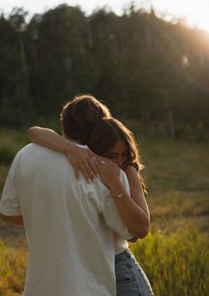 a man and woman hug each other in the field