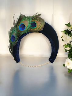 Many thanks for visiting our listings, please note our dispatch times are accurate please check them before ordering and if you need your item for an earlier date we ask that you message us first to make sure we can accommodate your delivery date. Presenting a truly stunning halo crown completed in a navy blue silk velvet with peacock feathers and jewelled black cabochon surrounded by diamante. Made with traditional millinery techniques this is a "hand blocked" design, which means it is hand made and hollow inside making it a delightfully lightweight addition to your outfit, attached by a hair millinery elastic ( tucked under your hair at the back of your neck a style preferred by the Princess of Wales) this unique design will really create a sensation wherever you go!  Measuring approxima Blue Feathered Wedding Fascinator, Peacock Feather Headband, Elegant Blue Headband Fascinator, Adjustable Blue Feathered Headpiece, Blue Feathered Headband Fascinator, Feather Headpiece, Halo Headband, Peacock Feathers, Peacock Feather