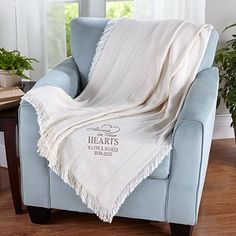 a blue chair with a white blanket on it and a potted plant in the corner