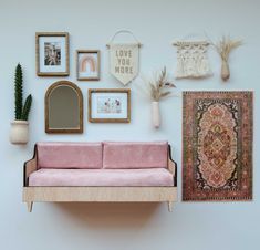 a pink couch sitting next to a wall with pictures on it