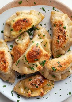 some dumplings are sitting on a plate with parsley sprinkled around them