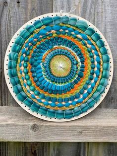 a blue and green plate sitting on top of a wooden fence