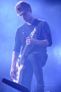 a young man playing an electric guitar on stage