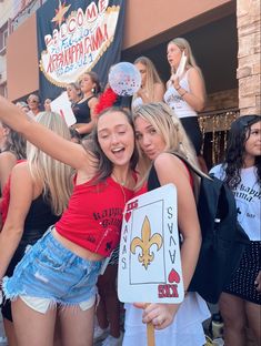 two girls are posing for the camera with their arms in the air and one girl is holding a sign that says welcome to new orleans