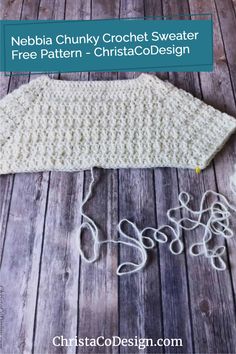 a crochet sweater sitting on top of a wooden floor next to some yarn