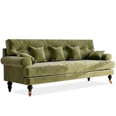 a green velvet couch with many pillows on the armrests and back rests against a white background