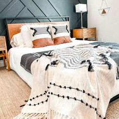 a large bed with two pillows on top of it and a blanket over the headboard