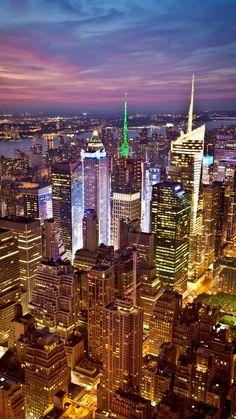 new york city skyline at night with the empire building lit up in green and blue