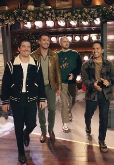 three men are walking down the runway in front of christmas decorations and lights on display