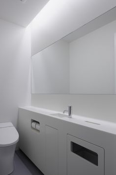 a white toilet sitting next to a bathroom sink under a large mirror above it's counter